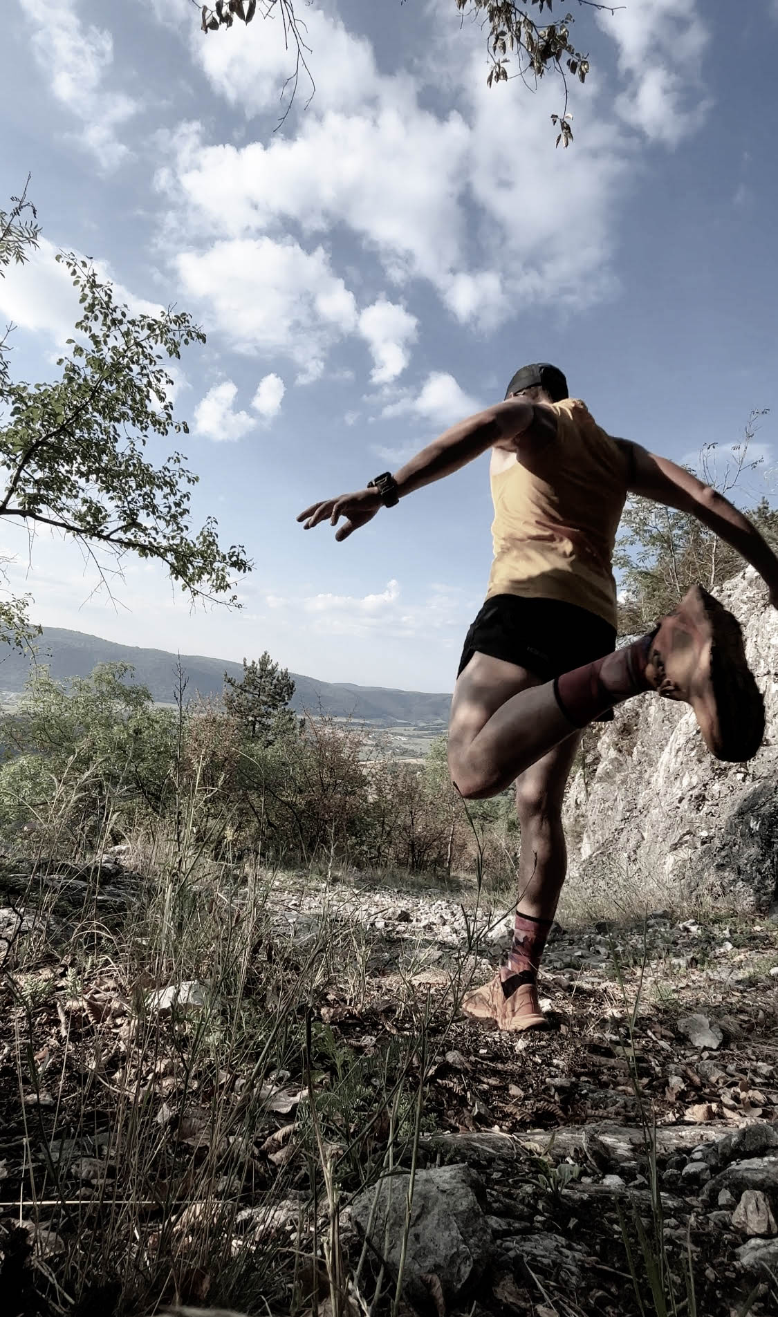 Runner descending a hill amidst natural surroundings.