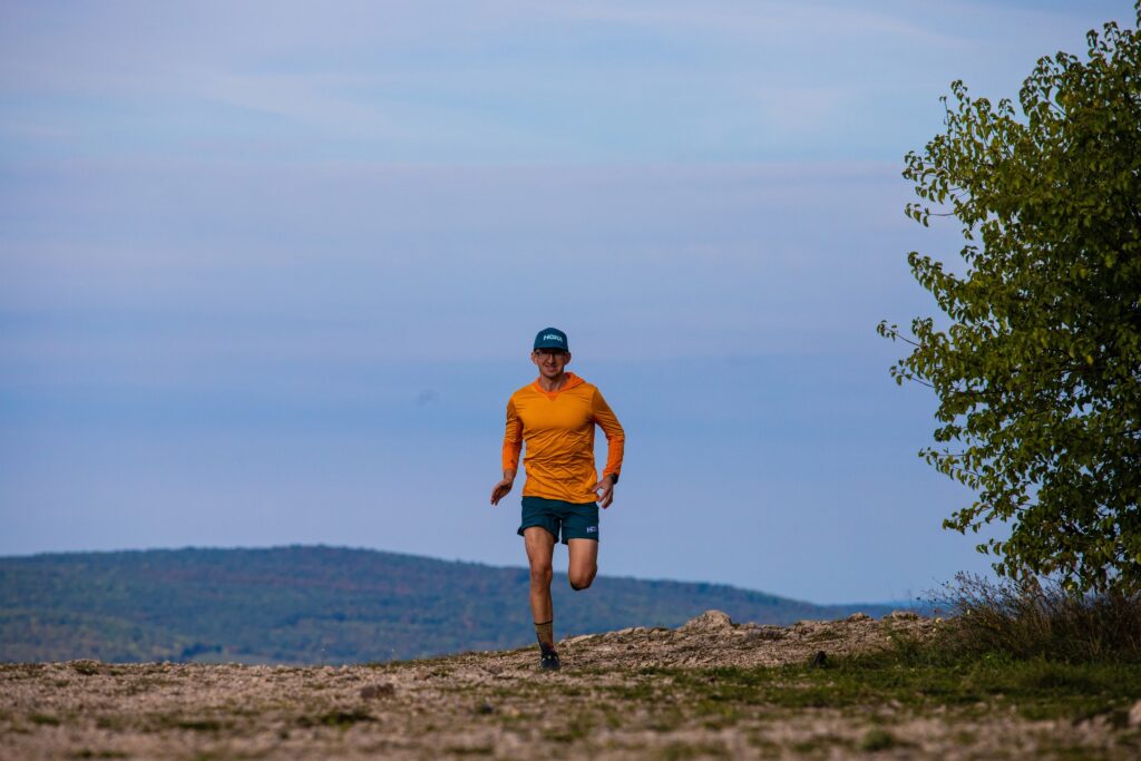 Patrik Milata, founder of Running Camps, running forward with a beautiful landscape in the background.